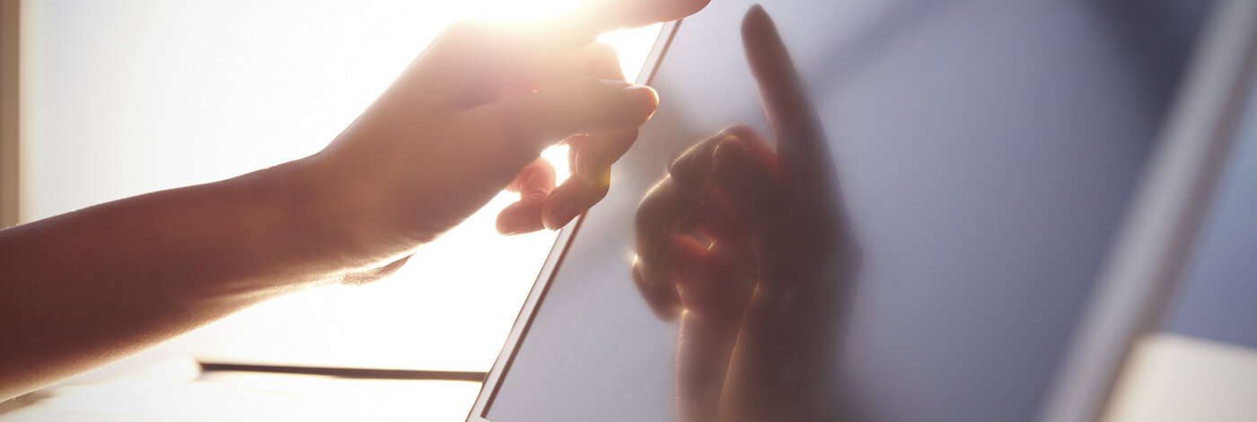 Käsi koskee kannettavaa auringonvalossa